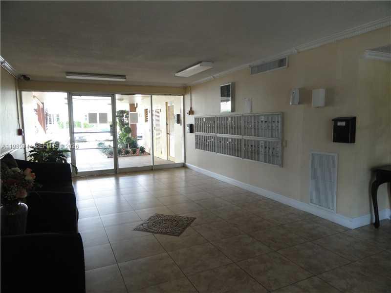 A glass-fronted building entrance features tiled flooring and a set of mailboxes inside — 16410 Miami Dr # 504, North Miami Beach FL 33162, NORTH MIAMI BEACH, FL
