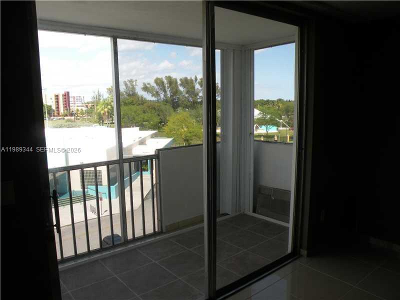 A hallway features beige tiled flooring, a mirrored wall, and a decorative wall hanging — 16410 Miami Dr # 504, North Miami Beach FL 33162, NORTH MIAMI BEACH, FL