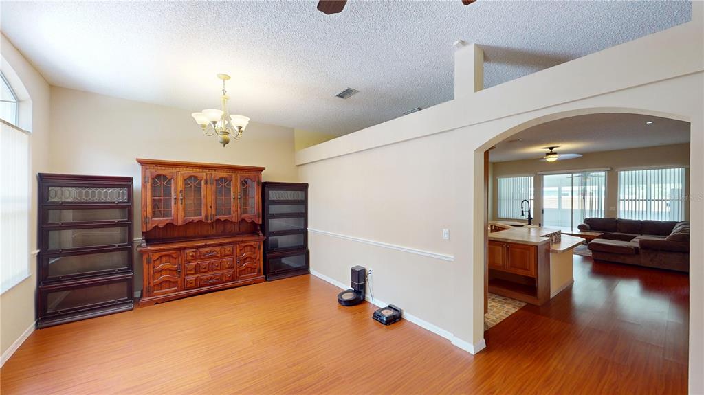 A dining room features wood flooring, a large hutch, and an arched opening to the kitchen — 26 LLOLEETA PATH, PALM COAST, FL