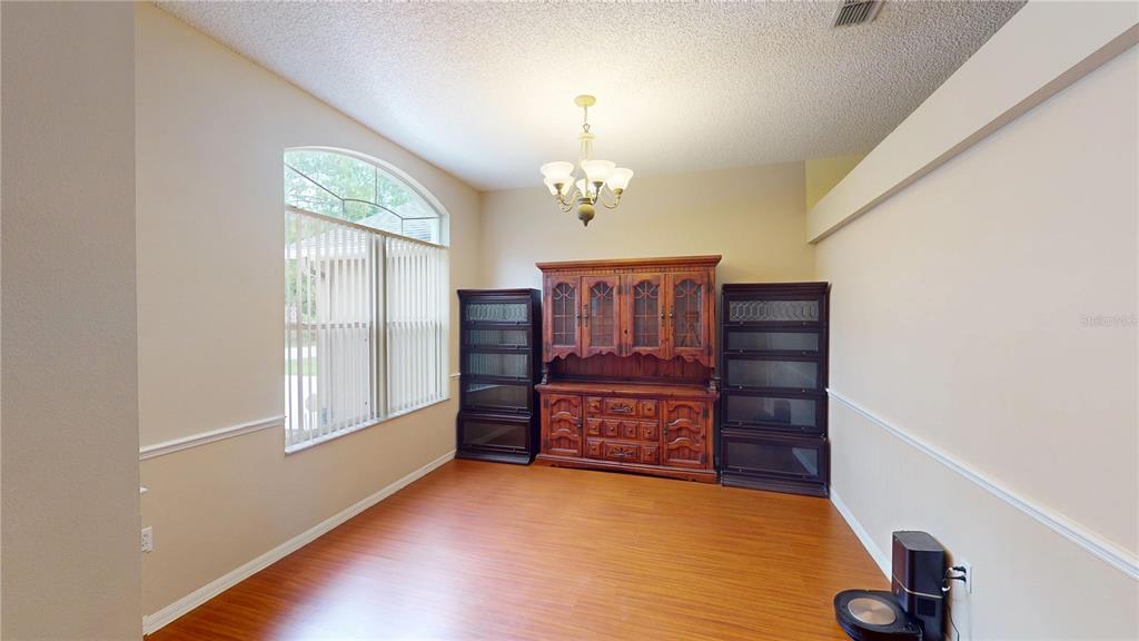 A dining room features wood-look flooring, a large hutch, and an arched window with blinds — 26 LLOLEETA PATH, PALM COAST, FL