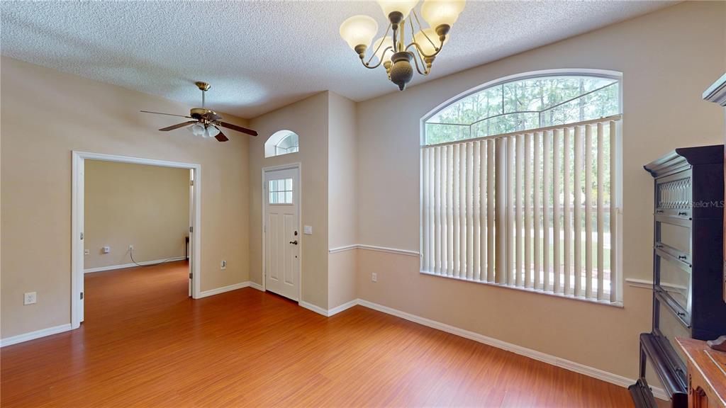 A dining room with wood-look flooring, a ceiling fan, a chandelier, and a large window — 26 LLOLEETA PATH, PALM COAST, FL