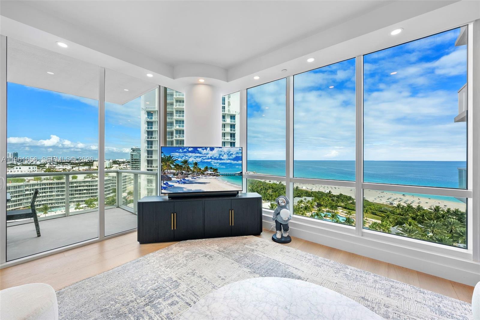 A living room features a television on a dark cabinet, a rug, and floor-to-ceiling windows — 100 S Pointe Dr, Miami Beach FL 33139, MIAMI BEACH, FL