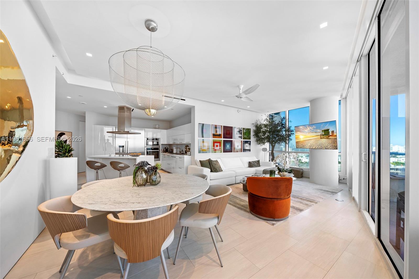 An open-concept living and dining area features a marble table, white sofa, and floor-to-ceiling windows — 100 S Pointe Dr, Miami Beach FL 33139, MIAMI BEACH, FL
