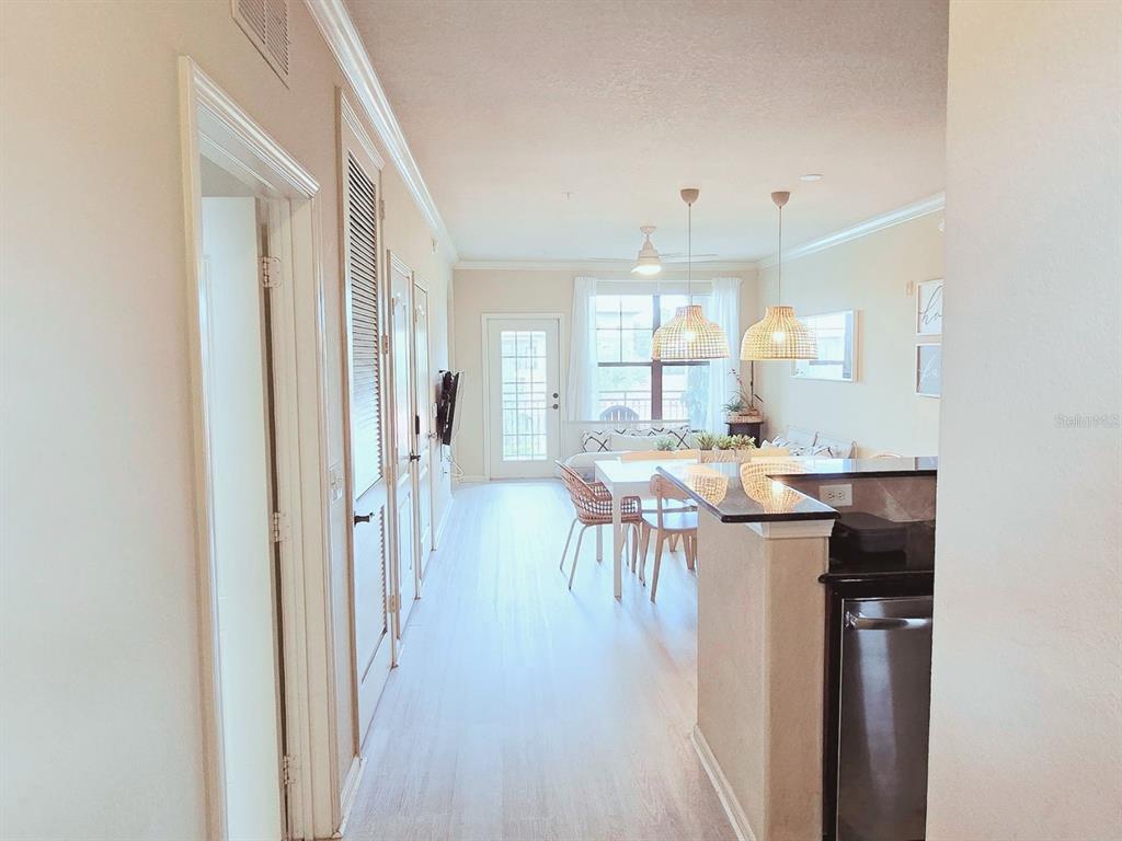 A view from a hallway looking into an open-concept kitchen and living area — 912 CHARO PARKWAY UNIT 233, DAVENPORT, FL