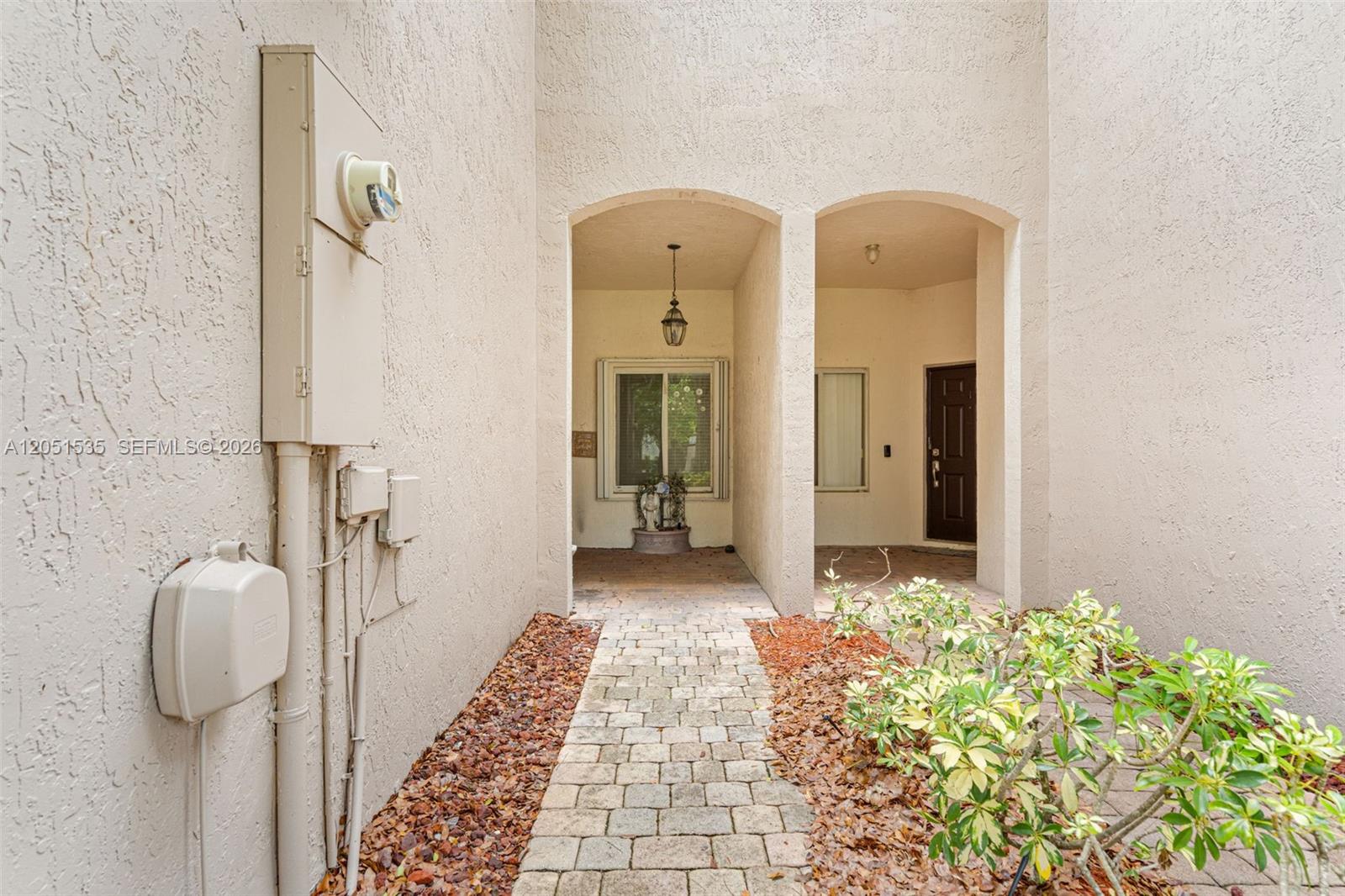 A paved walkway leads to a recessed entryway with two arched openings and a door — 1916 SE 23rd Ave, Homestead FL 33035, HOMESTEAD, FL