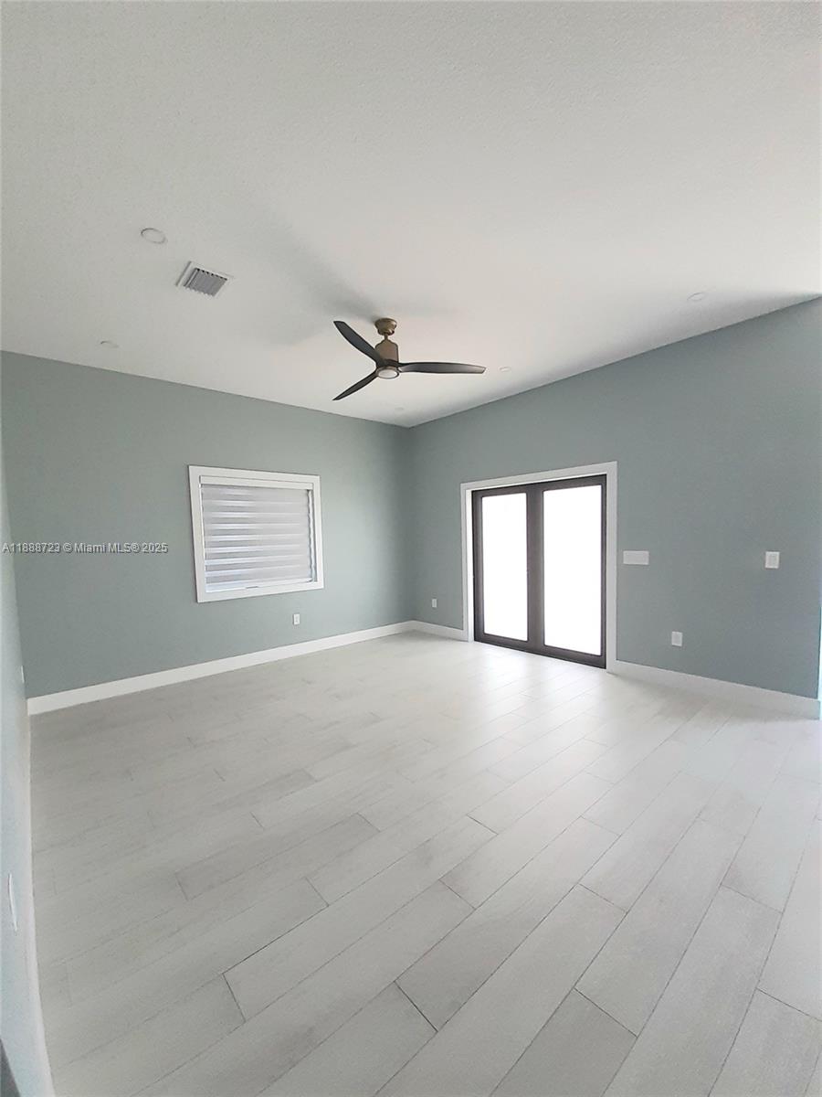 A room with light blue walls, white trim, light wood flooring, and a ceiling fan — 23 Jenny Ln, Key Largo FL 33037, KEY LARGO, FL