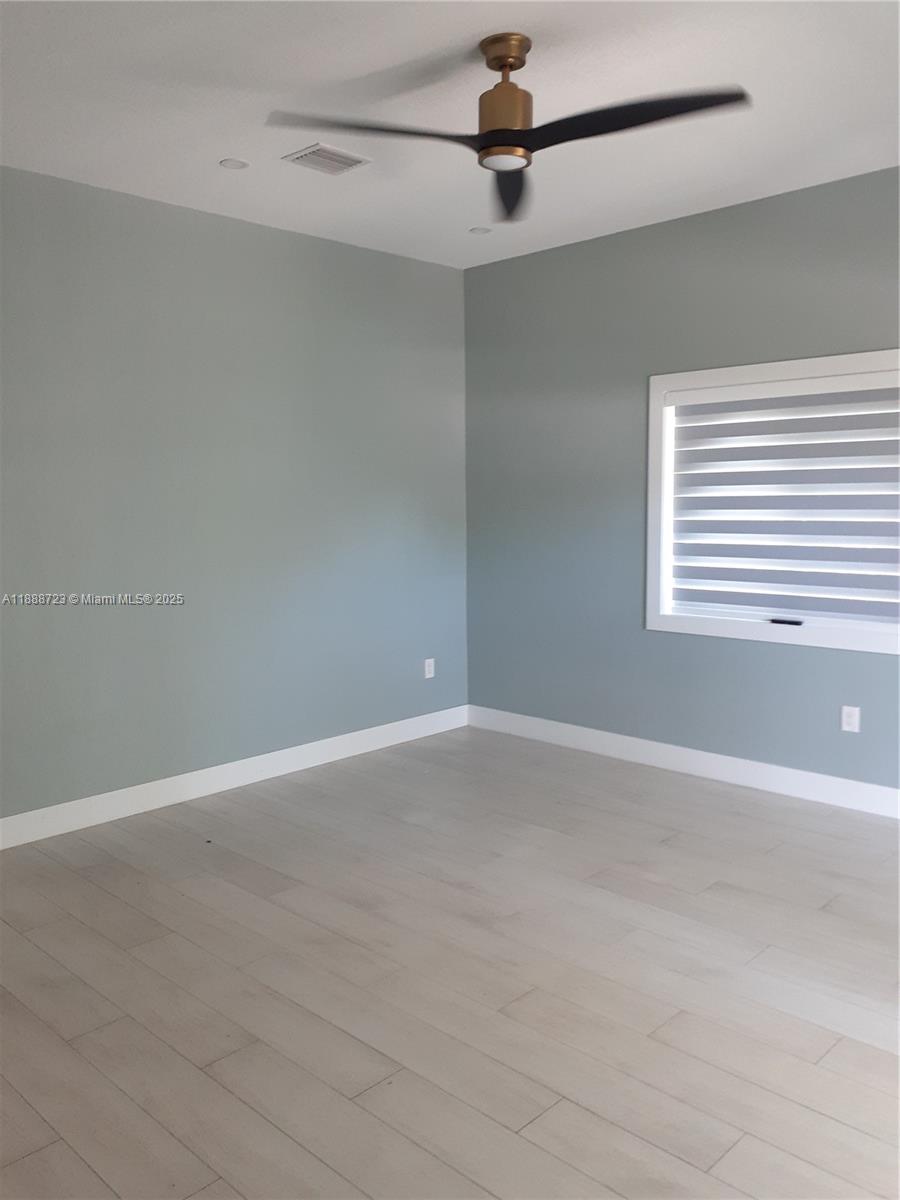 An empty room features light blue walls, white trim, wood-look flooring, and a ceiling fan — 23 Jenny Ln, Key Largo FL 33037, KEY LARGO, FL
