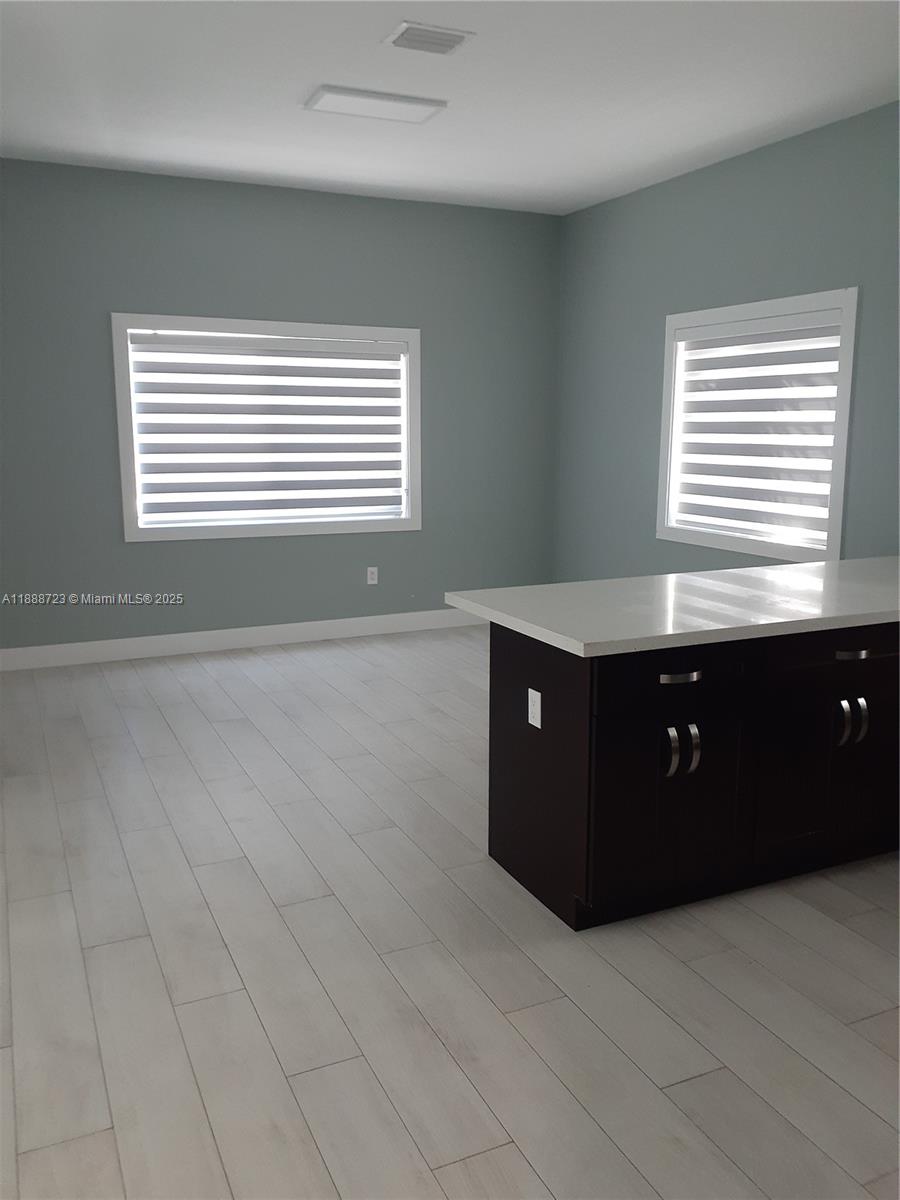 A room features light-colored wood flooring, gray walls, two windows with blinds, and a kitchen island — 23 Jenny Ln, Key Largo FL 33037, KEY LARGO, FL