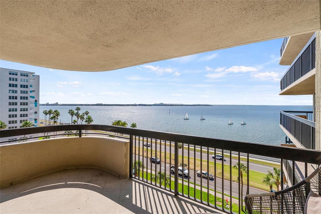 A balcony with a metal railing overlooks a road, palm trees, and a large bay — 2413 BAYSHORE BOULEVARD UNIT 803, TAMPA, FL