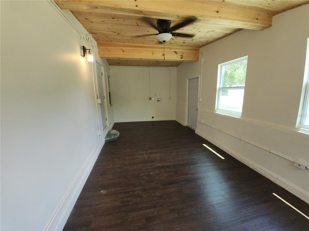 An interior room with dark wood-look flooring, white walls, and a natural wood-plank ceiling — 8569 W ADMIRAL BYRD LANE, CRYSTAL RIVER, FL