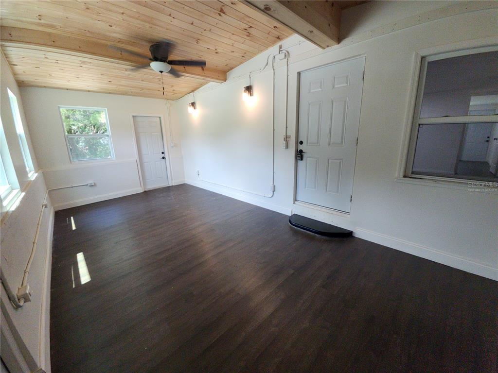 A sunroom features dark wood-look flooring, a wood-plank ceiling with a fan, and two doors — 8569 W ADMIRAL BYRD LANE, CRYSTAL RIVER, FL