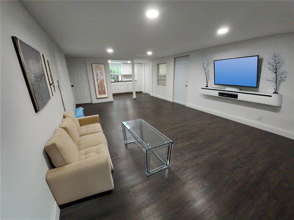 A living room with dark wood floors, a beige sofa, and a wall-mounted television — 8569 W ADMIRAL BYRD LANE, CRYSTAL RIVER, FL