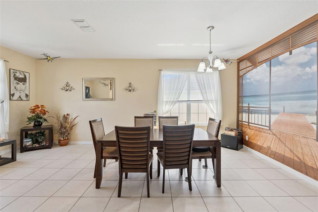 A dining room features a wooden table with six chairs, tiled floors, and a beach mural — 3409 BRANT STREET, ST CLOUD, FL