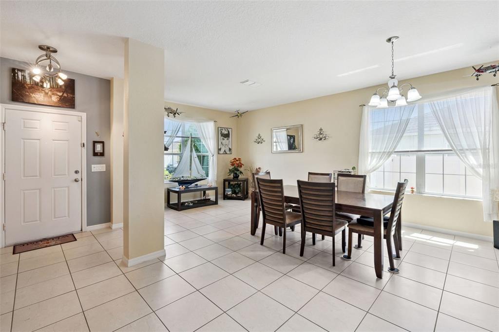 A dining room with tile floors, a wooden table, and a white front door — 3409 BRANT STREET, ST CLOUD, FL