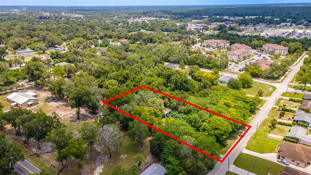An aerial view shows a rectangular plot of land outlined in red, containing trees and a small house — 497 W BERESFORD ROAD, DELAND, FL