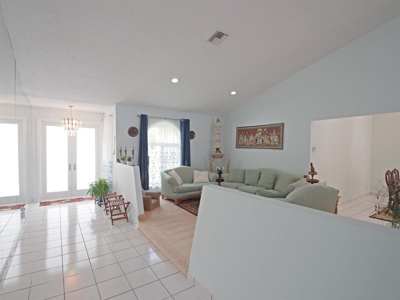 A living room features light blue walls, a carpeted seating area, and white tile flooring — 6300 NW 60th Way, Parkland FL 33067, PARKLAND, FL
