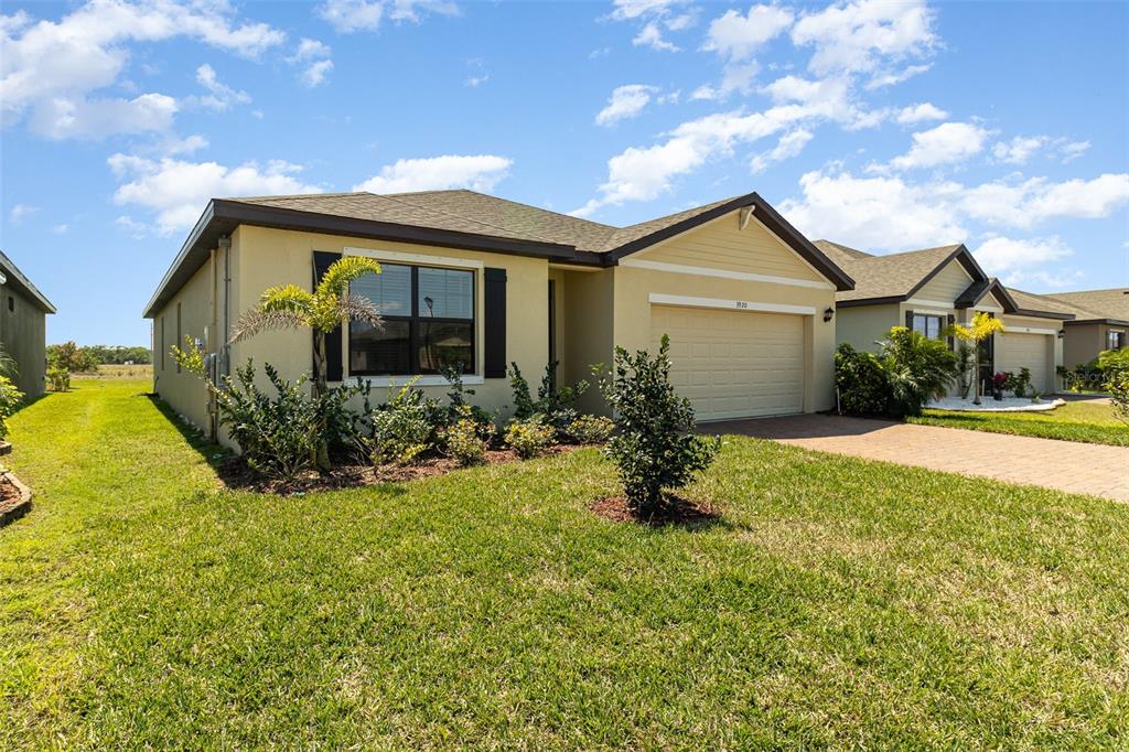 A single-story suburban house with a tan stucco exterior, a two-car garage, and landscaping — 3920 FOGGY MIST ROAD SE, PALM BAY, FL