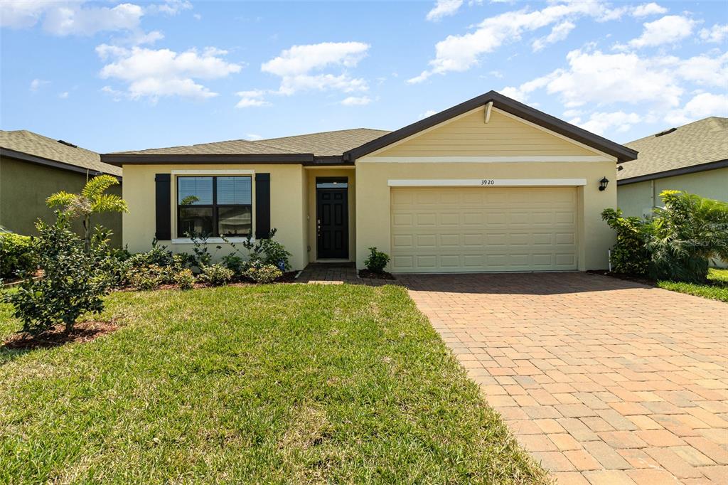 A single-story house with a beige exterior, a two-car garage, and a paved driveway — 3920 FOGGY MIST ROAD SE, PALM BAY, FL