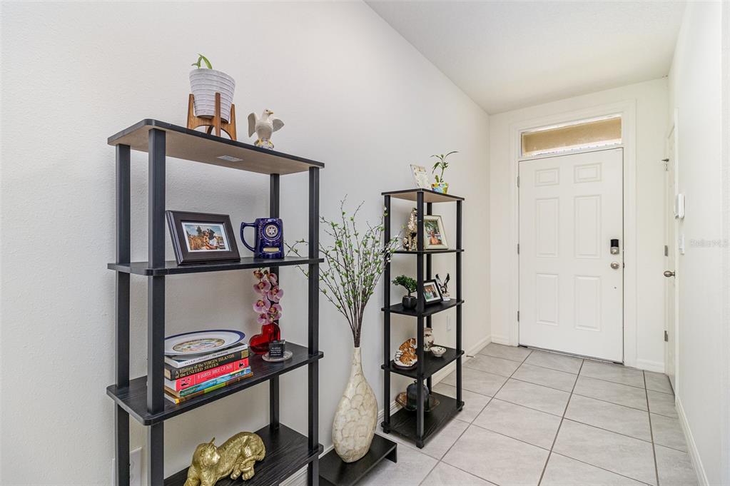 An entryway features two black shelving units, a decorative vase, and tiled flooring — 3920 FOGGY MIST ROAD SE, PALM BAY, FL
