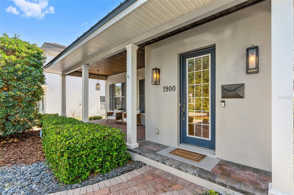 A covered front porch features brick pavers, white columns, and a blue glass-paneled front door — 1900 GERDA TERRACE, ORLANDO, FL