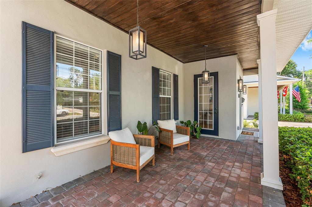 A covered porch features a brick floor, two wicker chairs, and dark wood ceiling planks — 1900 GERDA TERRACE, ORLANDO, FL
