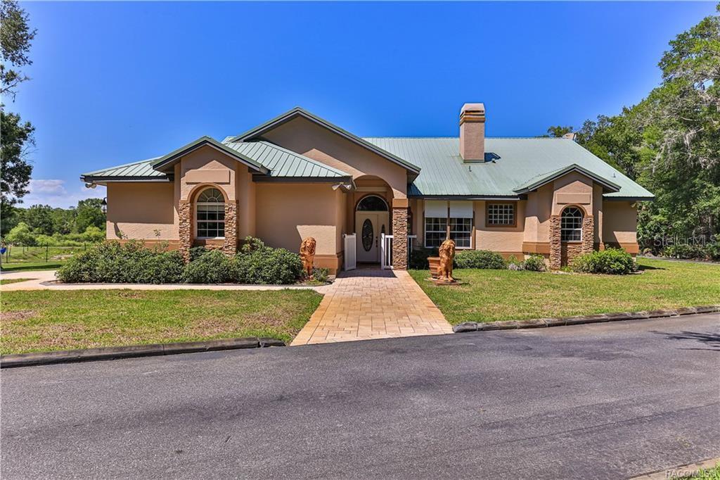 A single-story house with a metal roof, tan stucco exterior, and a stone-paved walkway — 5215 N HONEYCREEK TERRACE, CRYSTAL RIVER, FL