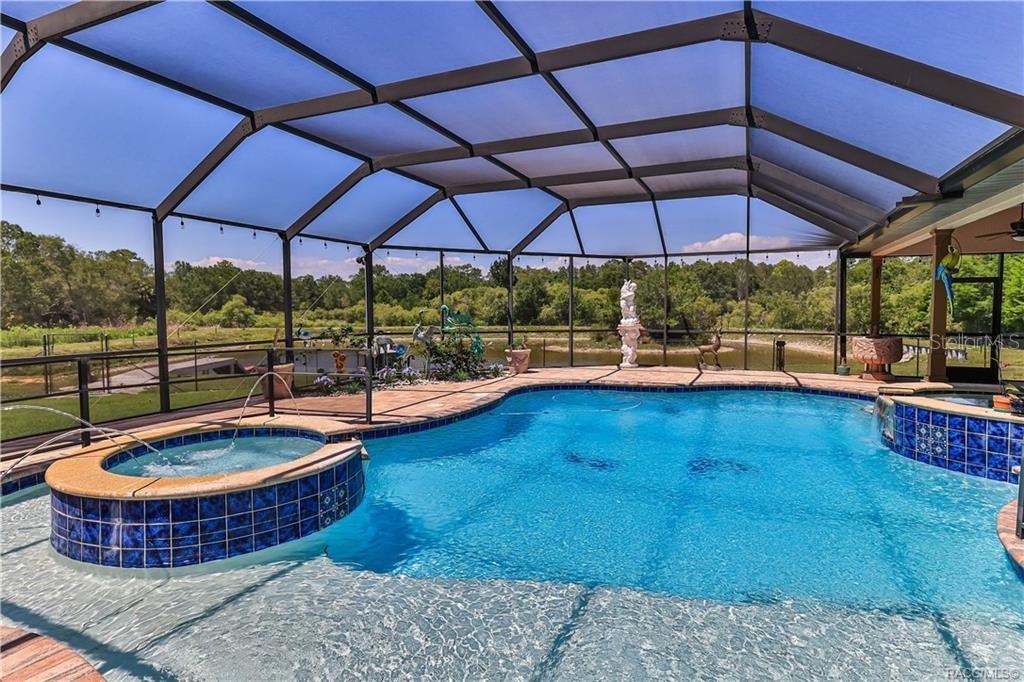 A screened-in swimming pool and hot tub overlook a pond and wooded area — 5215 N HONEYCREEK TERRACE, CRYSTAL RIVER, FL