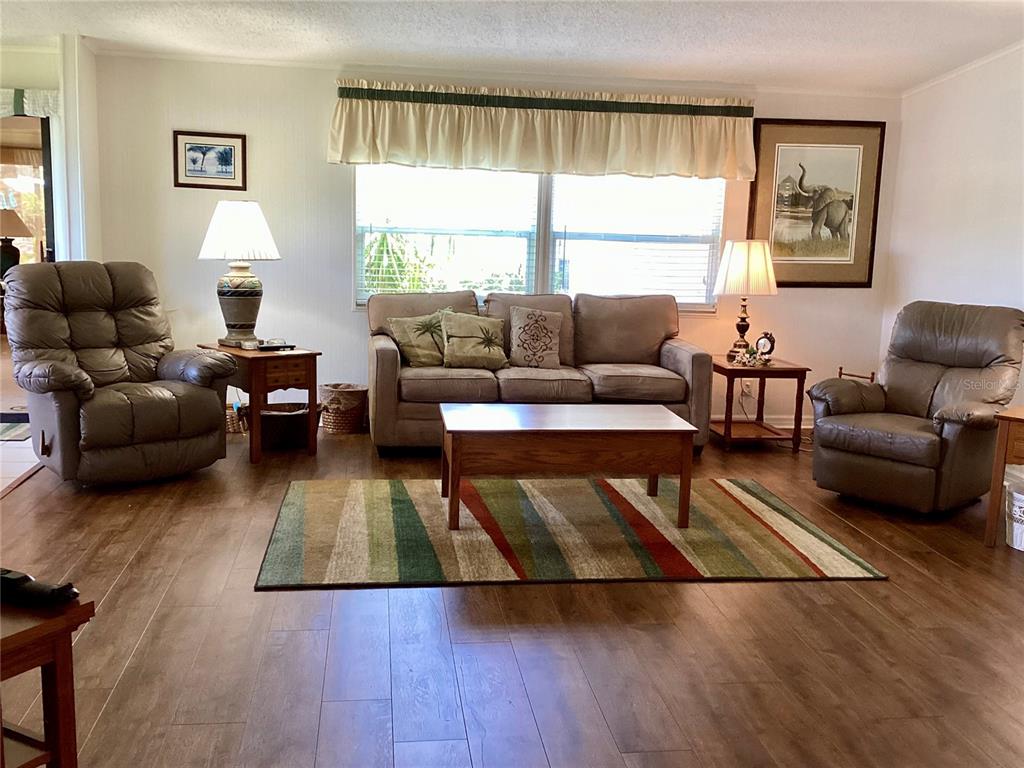A living room features a sofa, two recliners, a coffee table, and wood-look flooring — 8451 IMPERIAL CIRCLE, PALMETTO, FL
