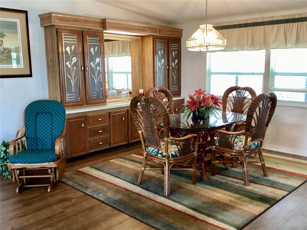 A dining room features a wooden hutch, a glass-topped table with wicker chairs, and area rug — 8451 IMPERIAL CIRCLE, PALMETTO, FL