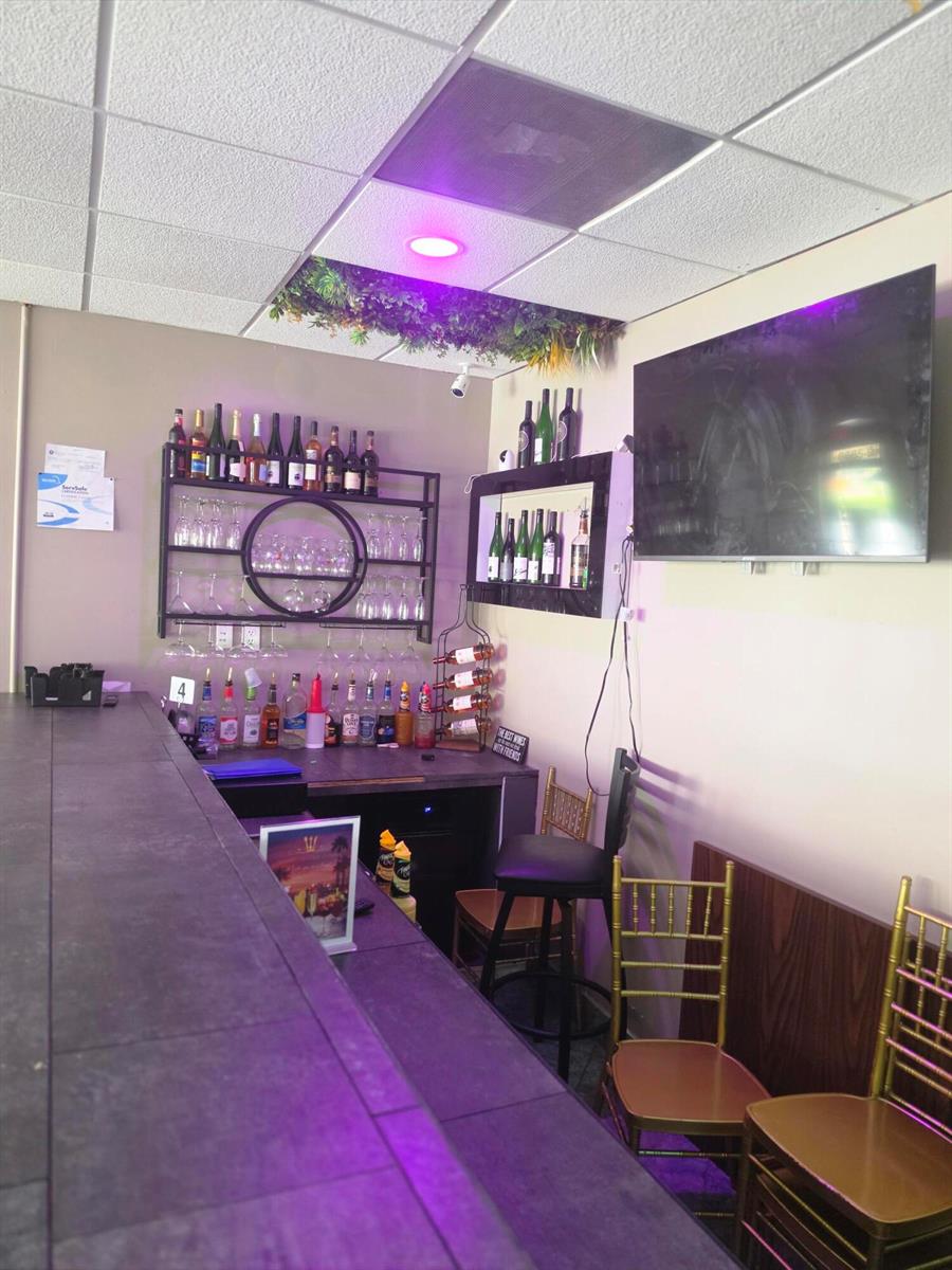 A small bar area features a dark countertop, wall-mounted bottle shelving, and gold-toned chairs — 6685 Lake Worth Road, FL 33467, FL