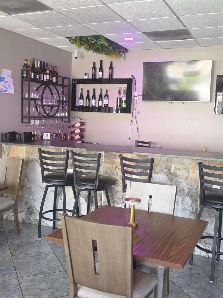 A bar area features a stone-faced counter, black stools, and wall-mounted wine bottle displays — 6685 Lake Worth Road, FL 33467, FL