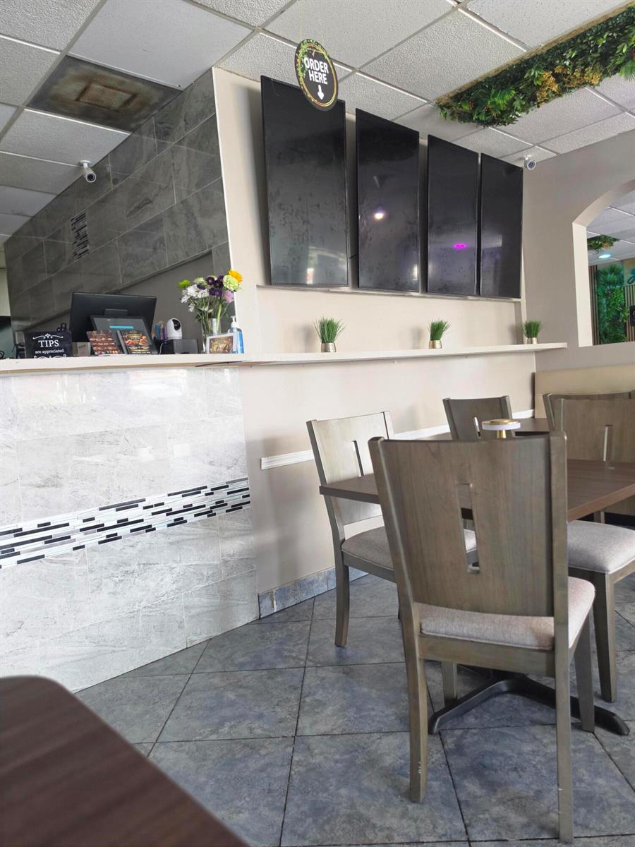 A restaurant interior features a service counter, digital menu boards, and wooden dining chairs — 6685 Lake Worth Road, FL 33467, FL