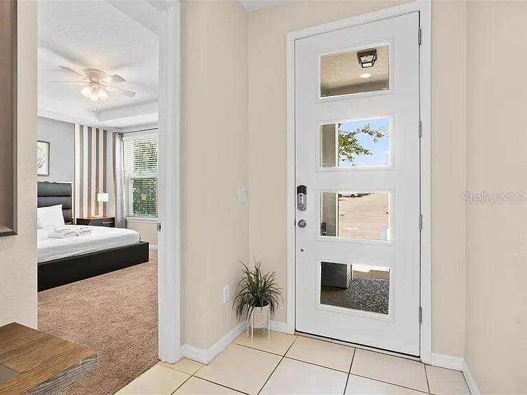 A white front door with four glass panels opens to a bedroom with carpet — 1521 CAREY PALM CIRCLE, KISSIMMEE, FL