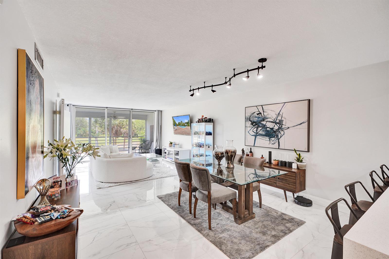 A bright, open-concept living and dining area features white marble floors and modern furniture — 545 Oaks Lane # 204, Pompano Beach FL 33069, POMPANO BEACH, FL