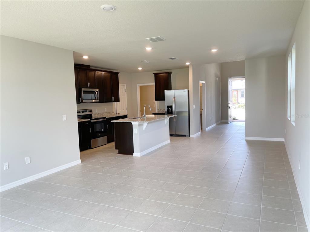 An open-concept kitchen features dark wood cabinets, granite countertops, and tile flooring — 3157 BELLA VISTA DRIVE, DAVENPORT, FL