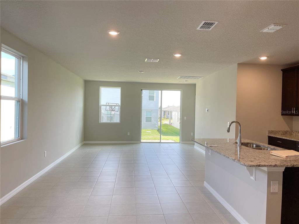 An open-concept living area features light tile flooring, a kitchen island, and sliding glass doors — 3157 BELLA VISTA DRIVE, DAVENPORT, FL