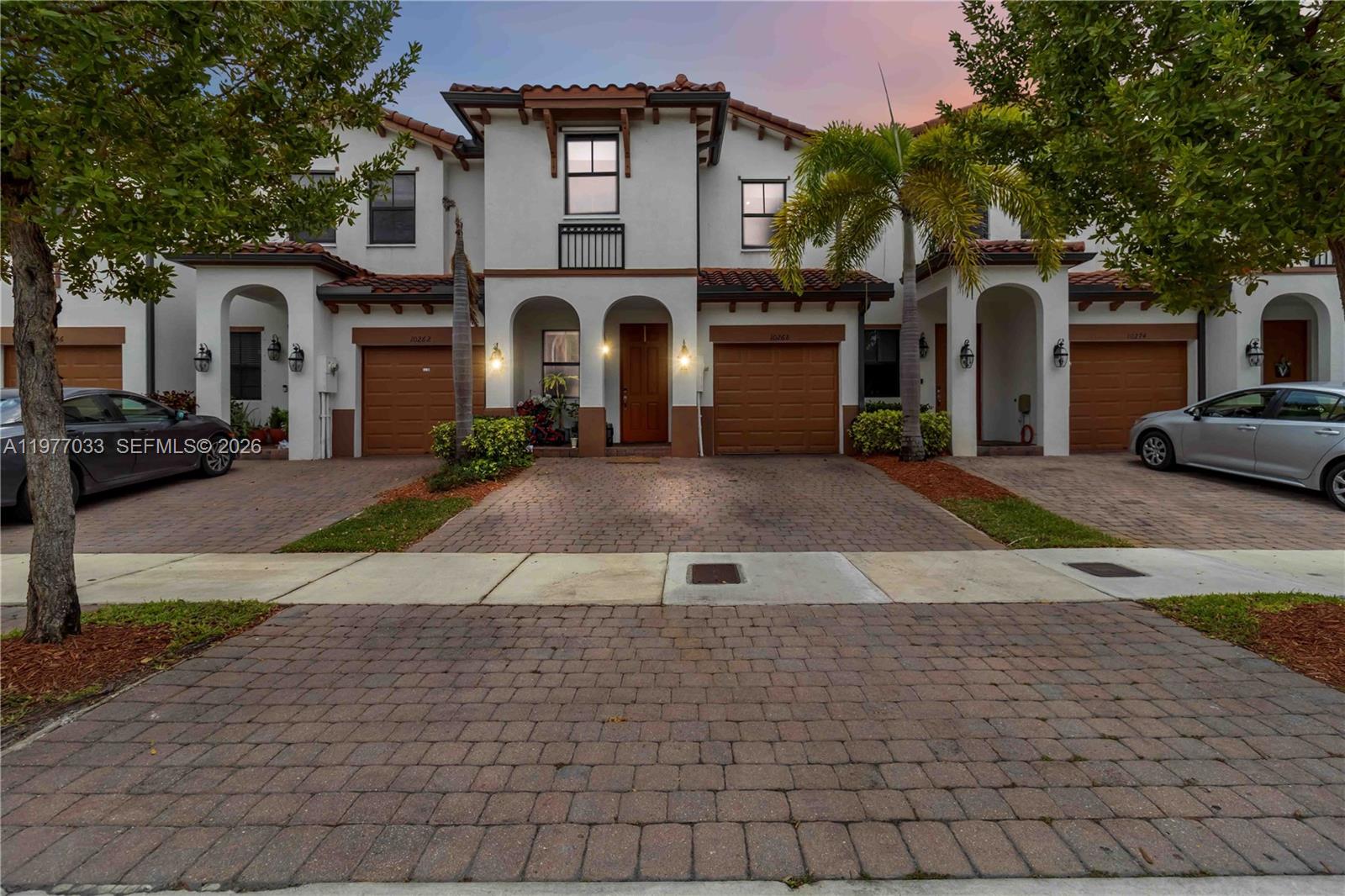 A row of two-story townhomes features stucco exteriors, brown garage doors, and paved driveways — 10268 NW 88th Ter, Doral FL 33178, DORAL, FL