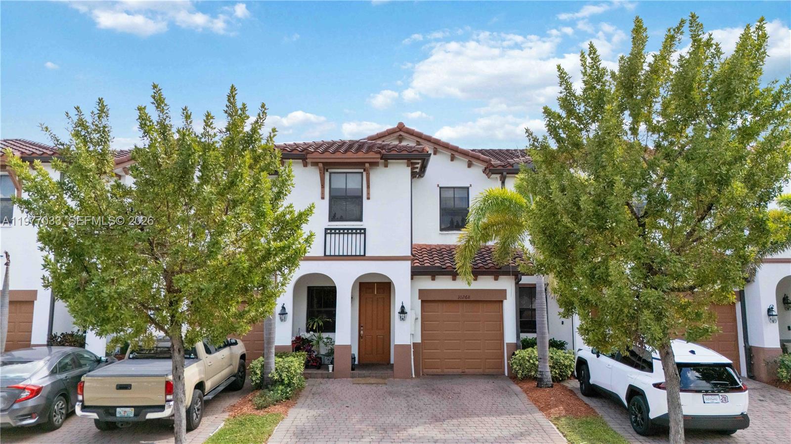 A two-story townhouse with a brown garage, white stucco exterior, and a paved driveway — 10268 NW 88th Ter, Doral FL 33178, DORAL, FL