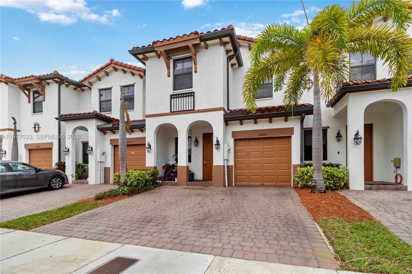 A row of two-story townhouses features white stucco walls, brown trim, and brick-paved driveways — 10268 NW 88th Ter, Doral FL 33178, DORAL, FL