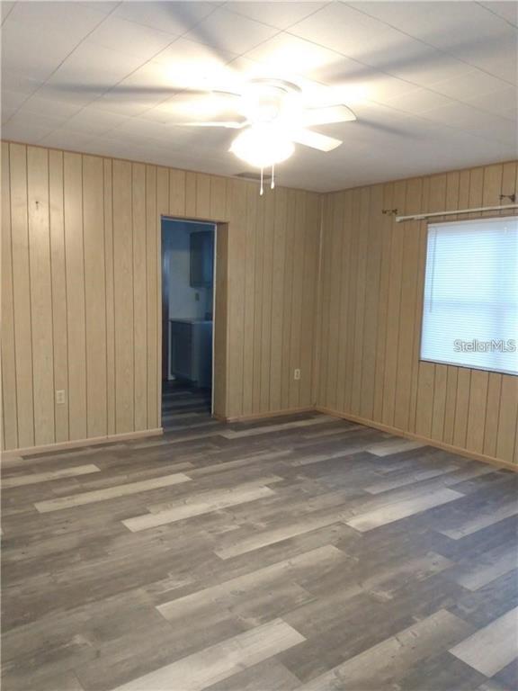 A room with wood-paneled walls, a ceiling fan, and gray wood-look flooring — 110 ORANGE AVENUE, WINTER HAVEN, FL