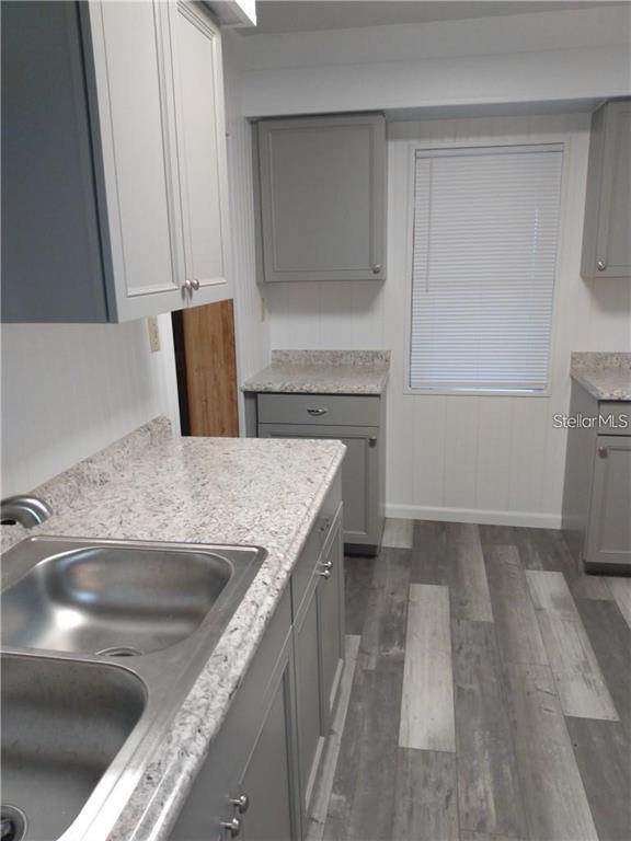 A kitchen features gray cabinets, speckled laminate countertops, a double sink, and wood-look flooring — 110 ORANGE AVENUE, WINTER HAVEN, FL