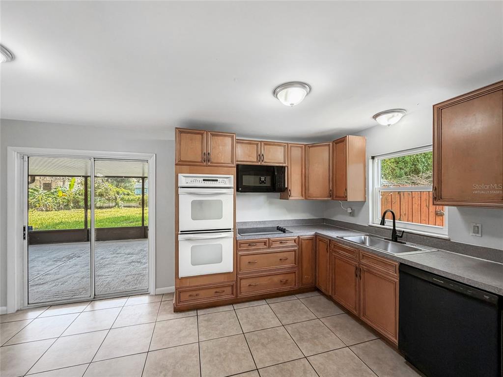 A kitchen with wooden cabinets, white double wall ovens, and a sliding glass door — 602 18TH STREET, ORLANDO, FL