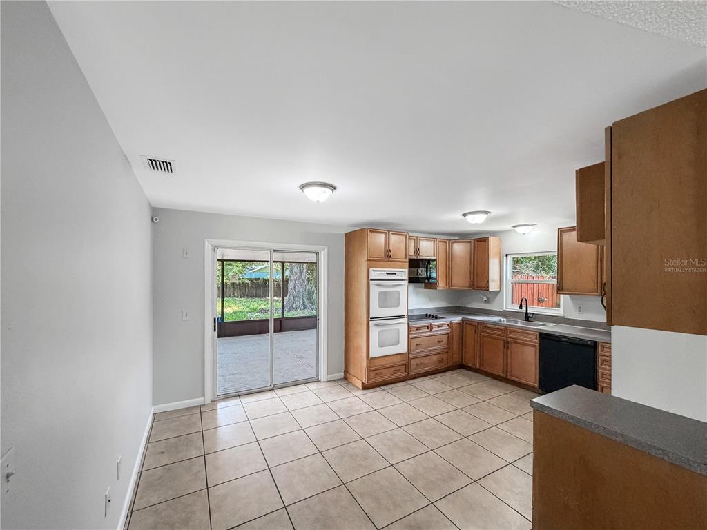A kitchen with light wood cabinets, tile flooring, and a sliding glass door to a patio — 602 18TH STREET, ORLANDO, FL