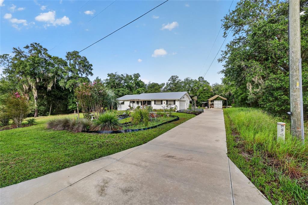 A white single-story house sits at the end of a long concrete driveway — 4500 SW FRESHWATER COURT, DUNNELLON, FL