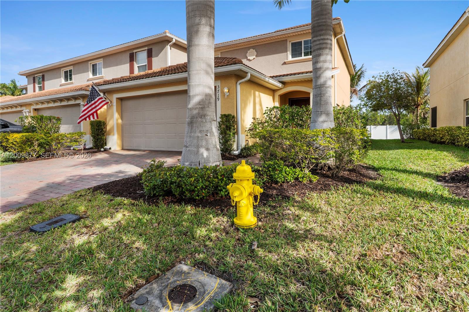 A yellow fire hydrant sits on the lawn in front of a two-story suburban home — FORT MYERS, FL