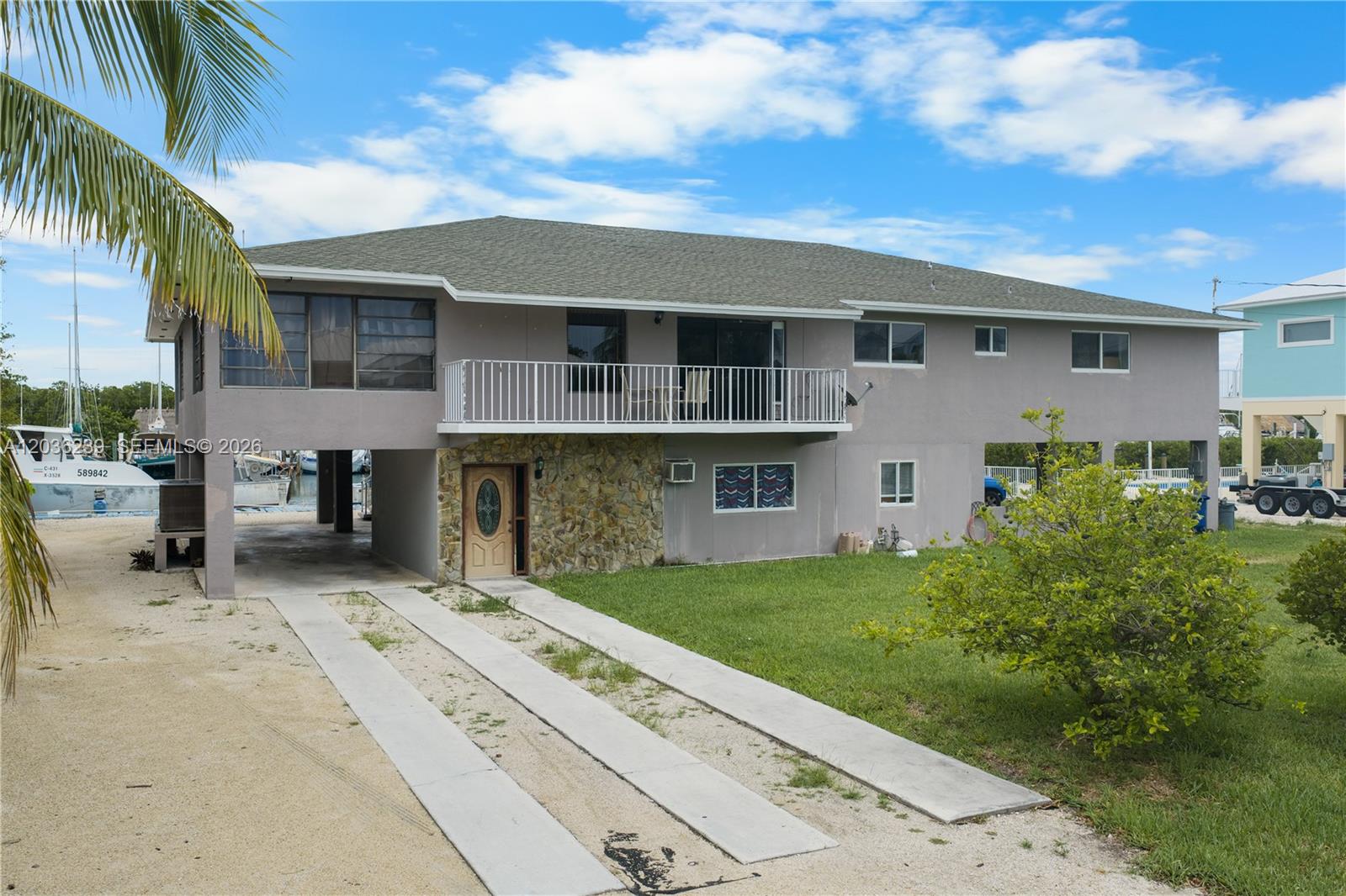 A two-story stilt house with a stone-accented entrance and a second-floor balcony — 2100 Avenue H, Marathon FL 33050, MARATHON, FL