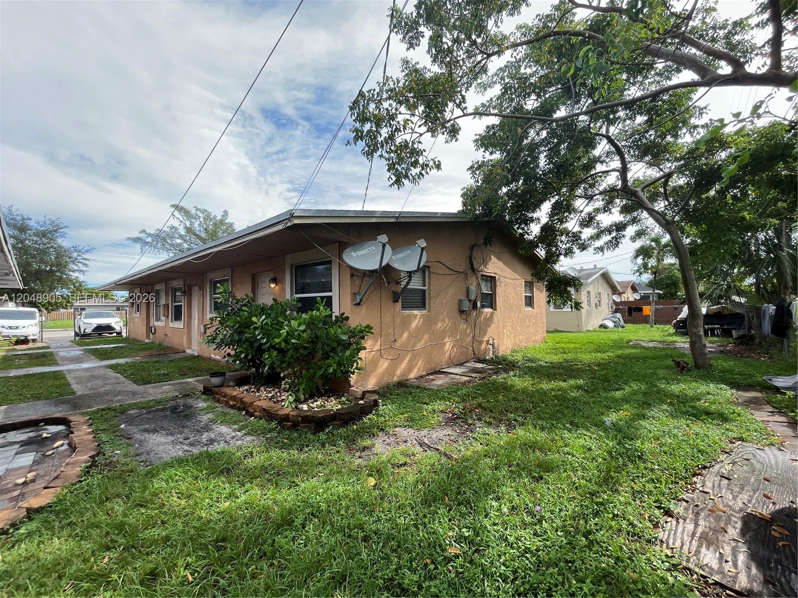 A single-story tan house with two satellite dishes sits on a grassy lot — 3028 NW 2nd St, Pompano Beach FL 33069, POMPANO BEACH, FL