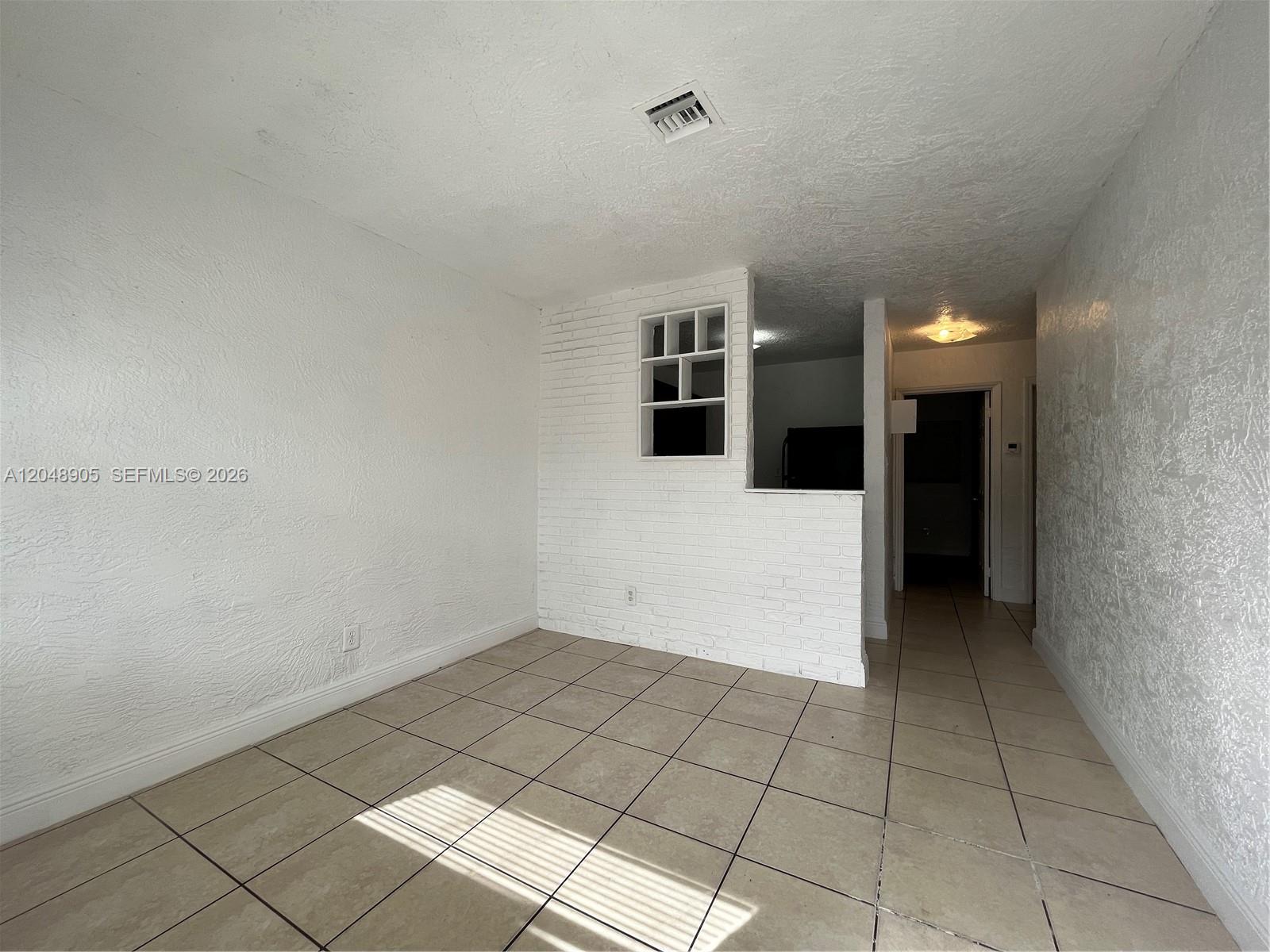An interior room features white textured walls, a white brick partition, and beige tile flooring — 3028 NW 2nd St, Pompano Beach FL 33069, POMPANO BEACH, FL