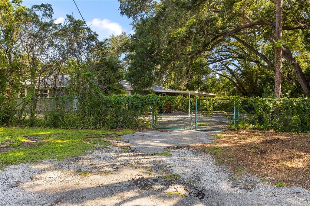 A gravel driveway leads to a fenced yard with a house and a carport — 2162 LONG BOW LANE, CLEARWATER, FL
