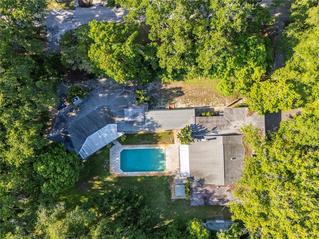 An aerial view shows a house with a swimming pool surrounded by dense green trees — 2162 LONG BOW LANE, CLEARWATER, FL